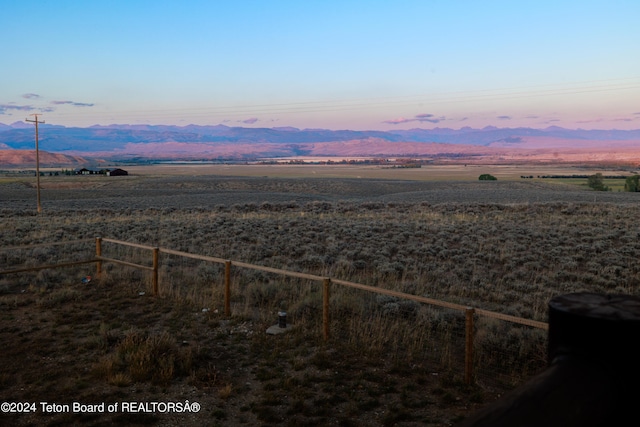 yard at dusk featuring a rural view and a mountain view