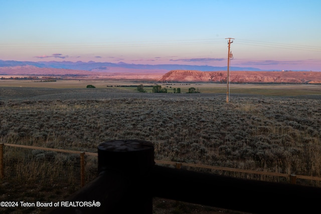 yard at dusk featuring a mountain view and a rural view