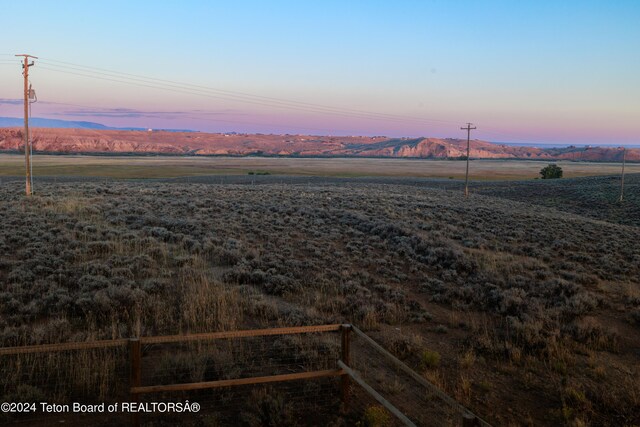 yard at dusk featuring a rural view