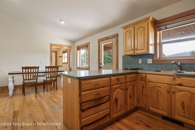 kitchen featuring kitchen peninsula, vaulted ceiling, sink, and plenty of natural light