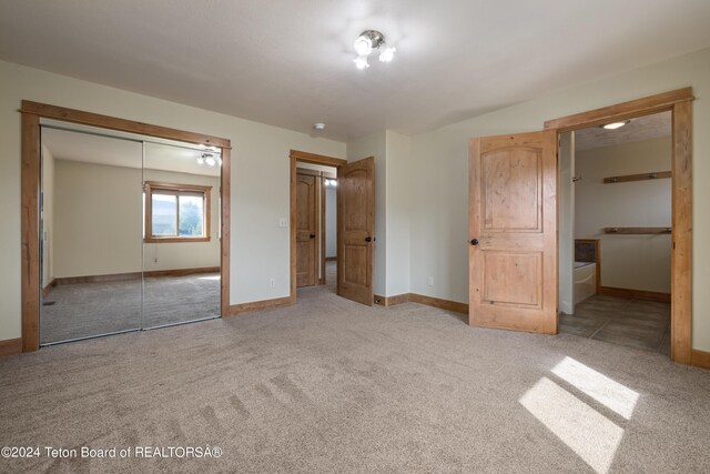 unfurnished bedroom featuring light carpet, a closet, and ensuite bathroom