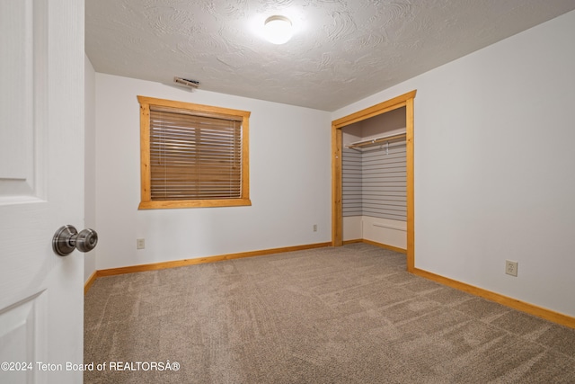 unfurnished room with a textured ceiling and carpet flooring