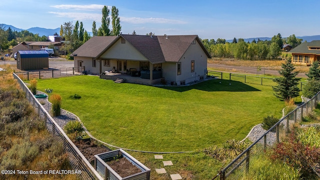 back of property featuring a yard, a shed, a patio, and a mountain view