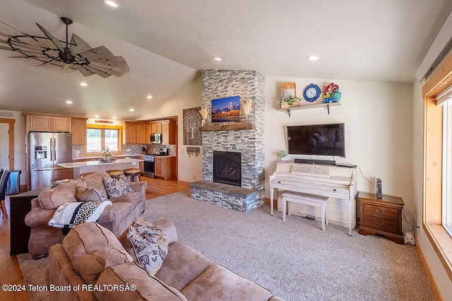 living room with lofted ceiling, ceiling fan, a fireplace, and light carpet