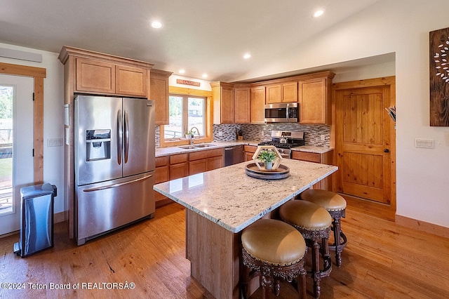 kitchen featuring a kitchen island, stainless steel appliances, sink, and light hardwood / wood-style flooring