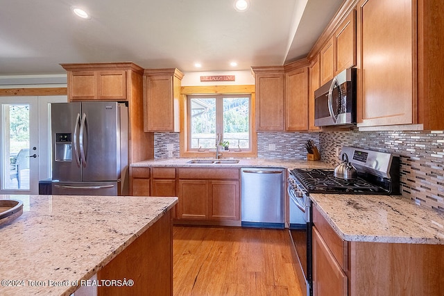 kitchen featuring light wood-type flooring, a wealth of natural light, stainless steel appliances, and sink