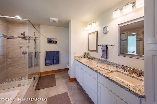 bathroom featuring vanity, toilet, tile patterned floors, and a shower with shower door