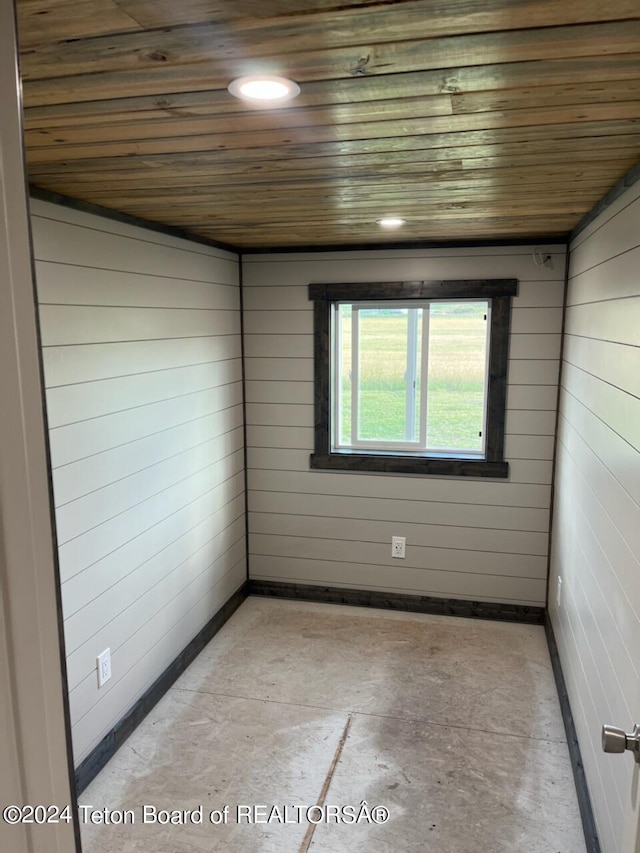 spare room featuring wooden ceiling and wooden walls