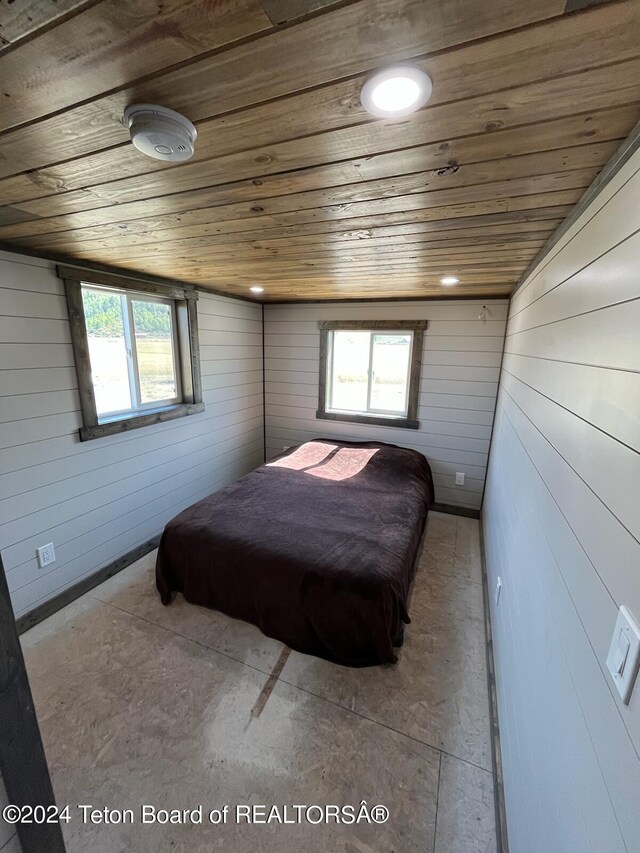 bedroom featuring wooden ceiling, multiple windows, and wooden walls