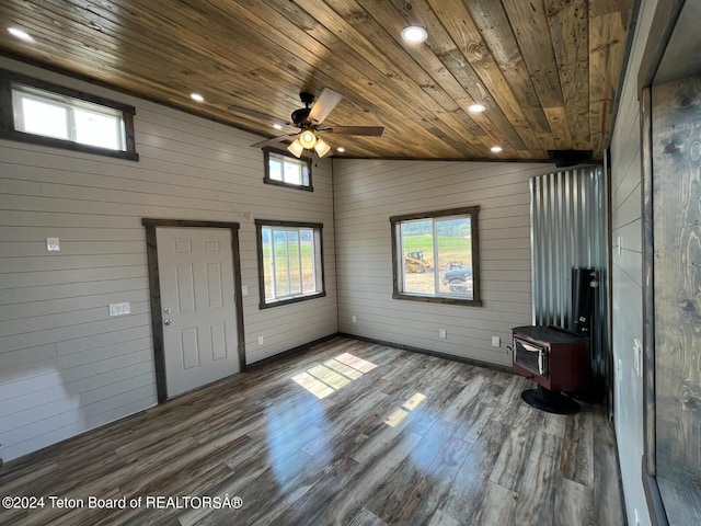 interior space with dark hardwood / wood-style floors, a wood stove, wood ceiling, lofted ceiling, and ceiling fan