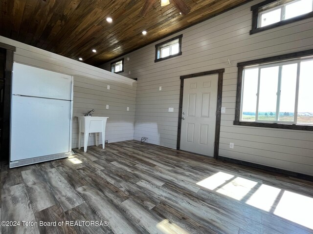 interior space with wood ceiling, dark wood-type flooring, wood walls, and a towering ceiling