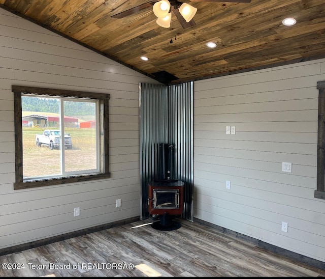 unfurnished living room featuring a wood stove, dark hardwood / wood-style flooring, ceiling fan, wood ceiling, and lofted ceiling