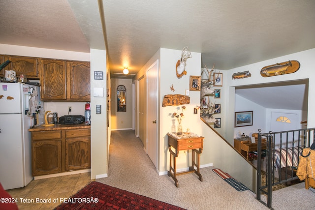 kitchen featuring white refrigerator, light colored carpet, and a textured ceiling