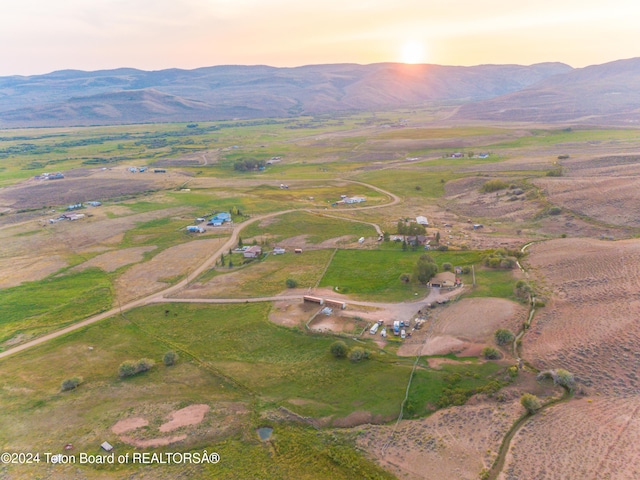 aerial view at dusk featuring a mountain view and a rural view