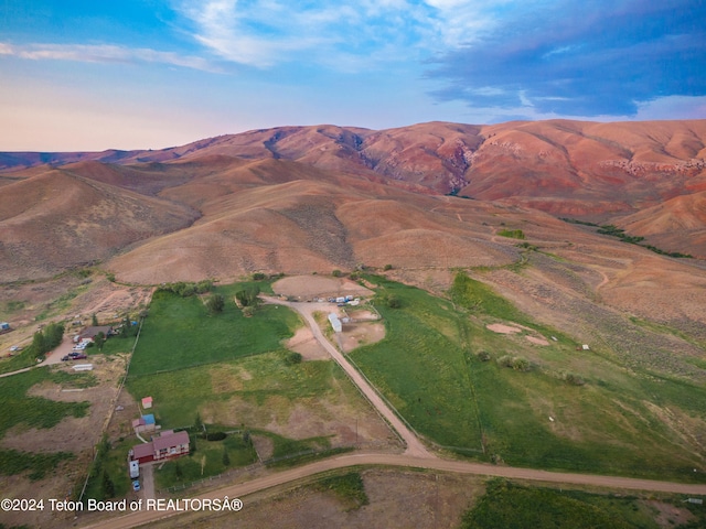 aerial view at dusk featuring a rural view and a mountain view