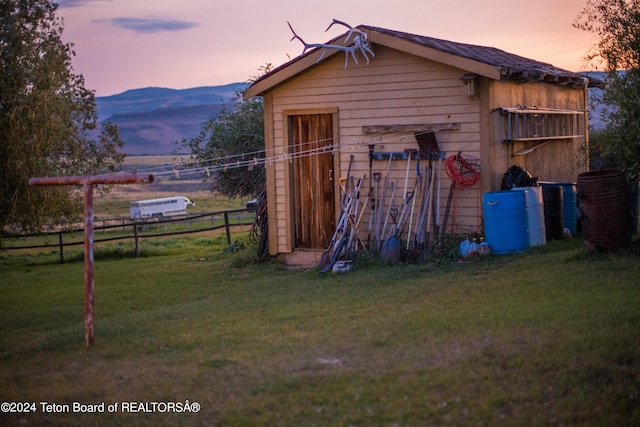 outdoor structure at dusk featuring a mountain view and a lawn