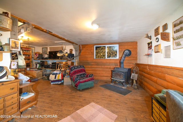 interior space featuring a wood stove, hardwood / wood-style floors, and wooden walls