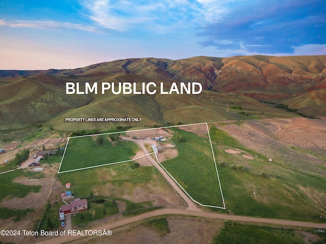 aerial view at dusk featuring a mountain view and a rural view