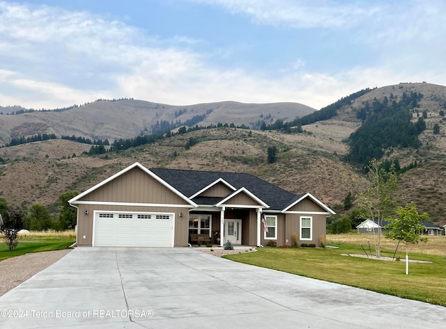 view of front of home with a mountain view, a front yard, and a garage