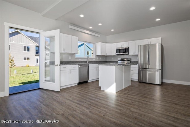 kitchen with appliances with stainless steel finishes, white cabinetry, a kitchen island, dark hardwood / wood-style floors, and sink