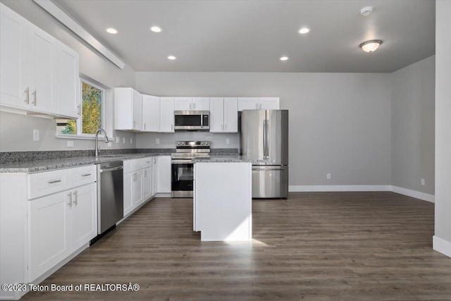 kitchen featuring light stone counters, a kitchen island, dark wood-type flooring, white cabinetry, and appliances with stainless steel finishes