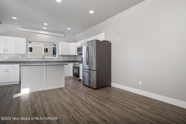 kitchen featuring white cabinets, a kitchen island, stainless steel appliances, dark hardwood / wood-style flooring, and dark stone countertops