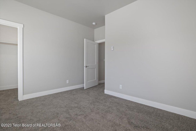 unfurnished bedroom with carpet flooring, a spacious closet, and a closet