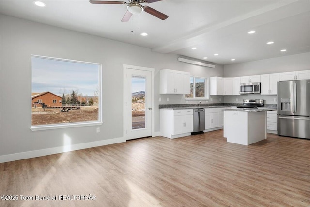 kitchen with white cabinetry, appliances with stainless steel finishes, a center island, and light wood-type flooring