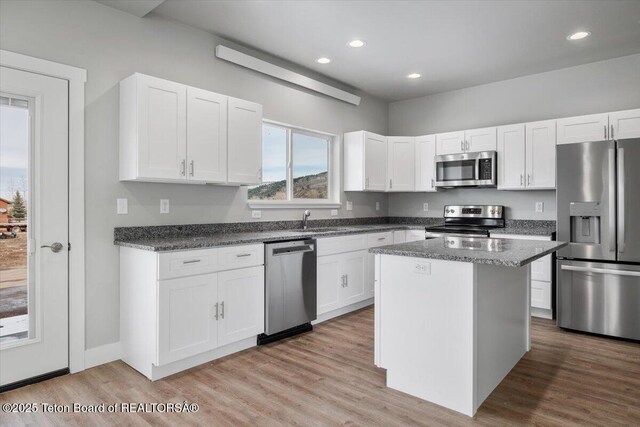 kitchen with dark stone countertops, a kitchen island, white cabinets, and appliances with stainless steel finishes