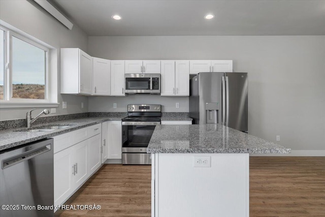 kitchen featuring sink, white cabinetry, stone countertops, appliances with stainless steel finishes, and a kitchen island