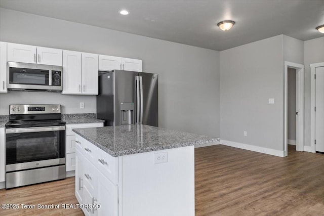 kitchen featuring white cabinetry, hardwood / wood-style flooring, stainless steel appliances, and a kitchen island