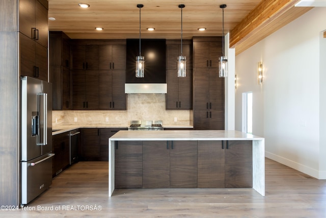 kitchen with light wood-type flooring, hanging light fixtures, wall chimney exhaust hood, and stainless steel appliances