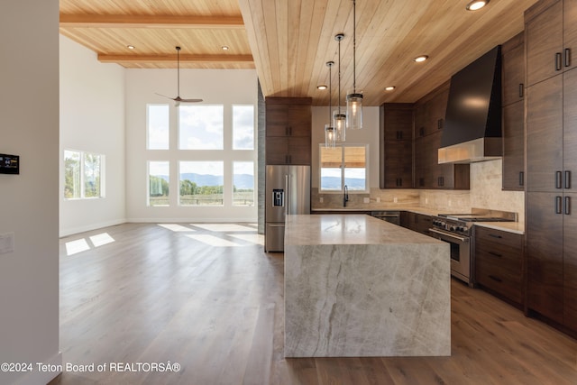 kitchen with custom exhaust hood, wood ceiling, a kitchen island, wood-type flooring, and appliances with stainless steel finishes