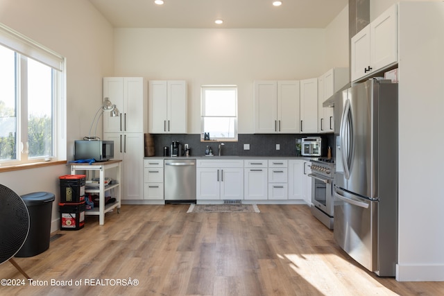 kitchen with white cabinets, appliances with stainless steel finishes, and a wealth of natural light