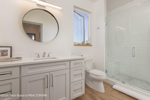 bathroom featuring an enclosed shower, vanity, toilet, and hardwood / wood-style flooring