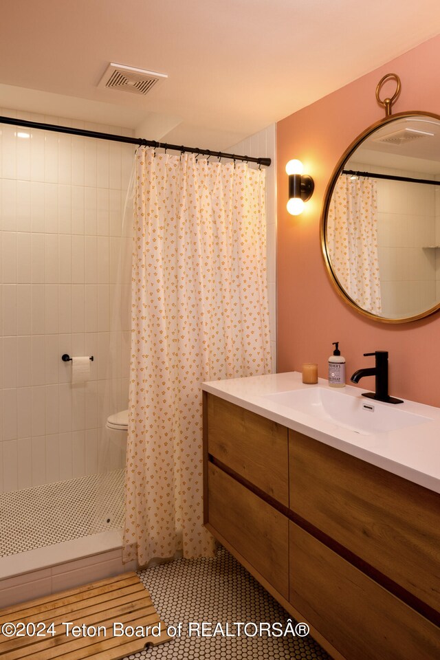 bathroom featuring vanity, curtained shower, toilet, and tile patterned floors