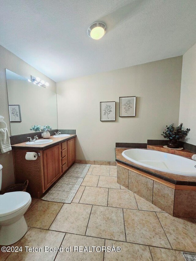 bathroom with vanity, a textured ceiling, a relaxing tiled tub, and toilet