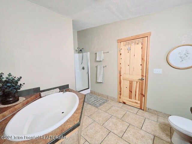 bathroom with a textured ceiling, shower with separate bathtub, and toilet