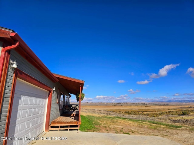 view of yard with a rural view, a garage, and a deck