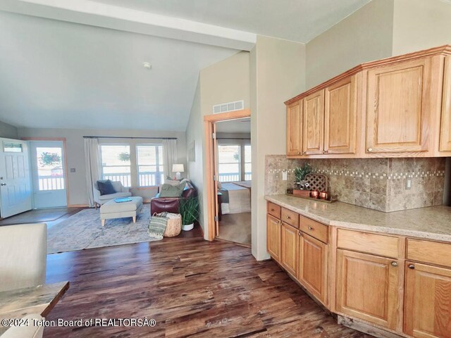 kitchen with decorative backsplash, light brown cabinets, dark wood-type flooring, and high vaulted ceiling