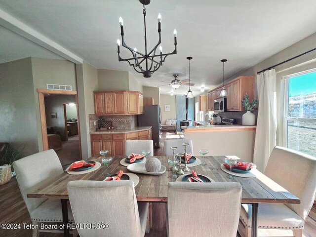 dining area with ceiling fan with notable chandelier and hardwood / wood-style flooring