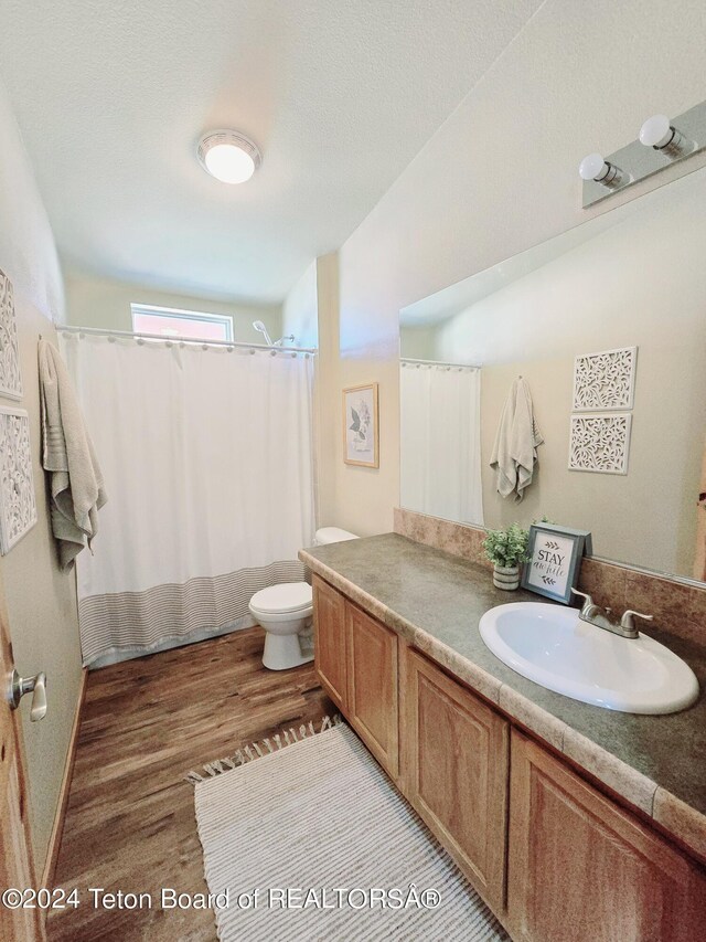 bathroom with vanity, a textured ceiling, hardwood / wood-style flooring, toilet, and a shower with shower curtain