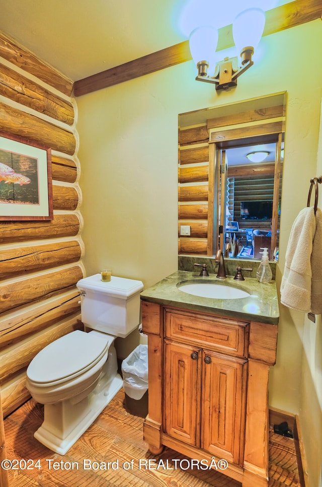 bathroom with log walls, vanity, and toilet