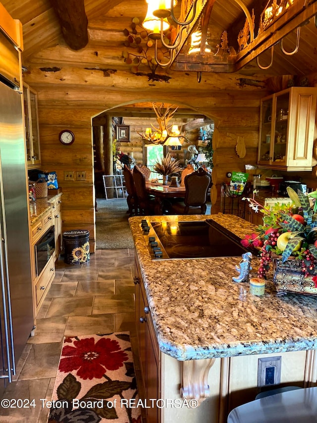 kitchen with light stone counters, hanging light fixtures, a chandelier, log walls, and black electric stovetop