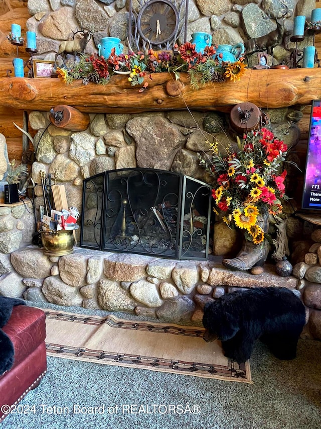 interior details featuring a stone fireplace and carpet flooring