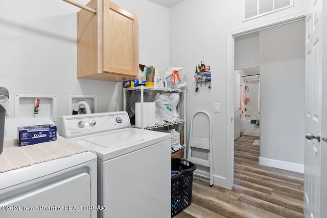 laundry room featuring cabinets, dark hardwood / wood-style floors, and washer and clothes dryer