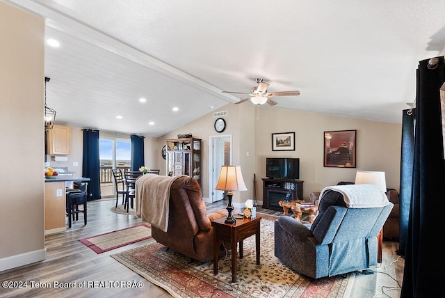 living room featuring ceiling fan, lofted ceiling with beams, and light wood-type flooring