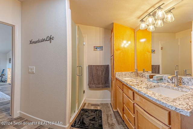 bathroom featuring hardwood / wood-style floors, vanity, a textured ceiling, and walk in shower