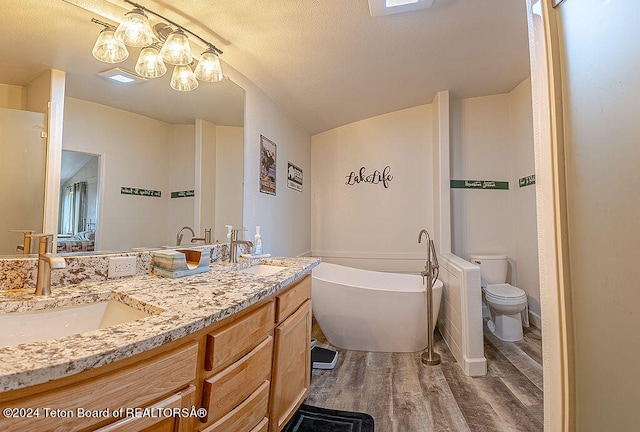 bathroom featuring a bathtub, a textured ceiling, vanity, hardwood / wood-style flooring, and toilet