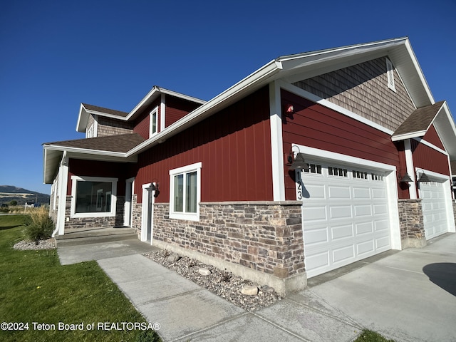 123 Creekside Ln, Swan Valley, ID 83449 - view of front of home with stone siding, concrete driveway, an attached garage, and a shingled roof